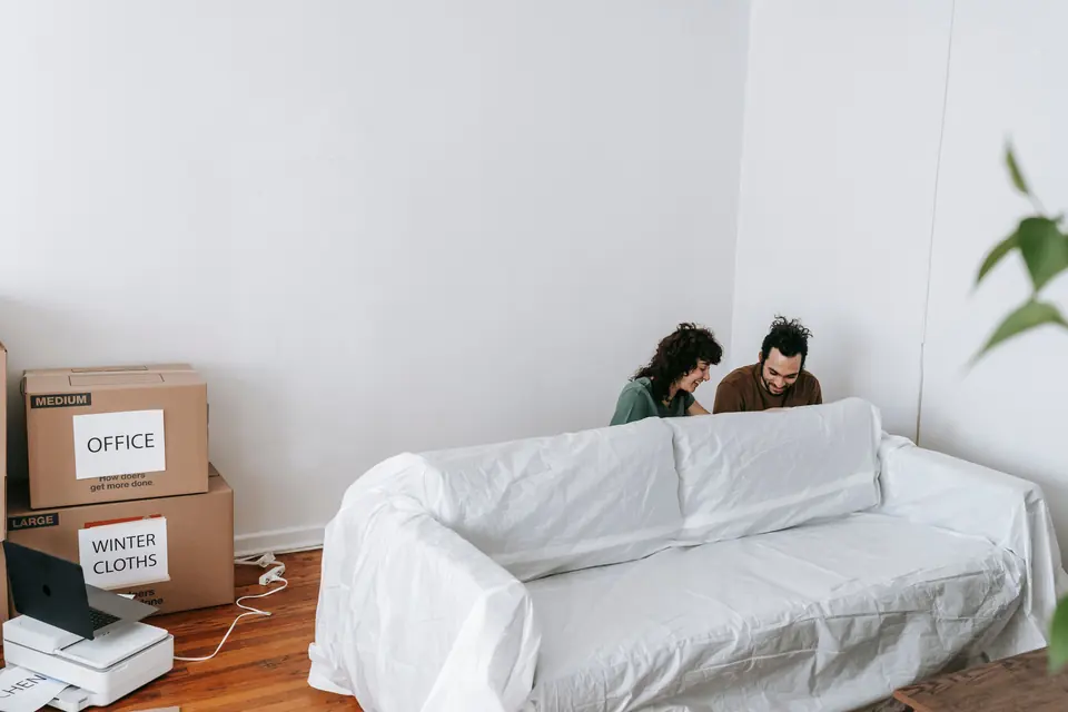 Büroumzug mit abgedecktem Sofa und beschrifteten Kartons