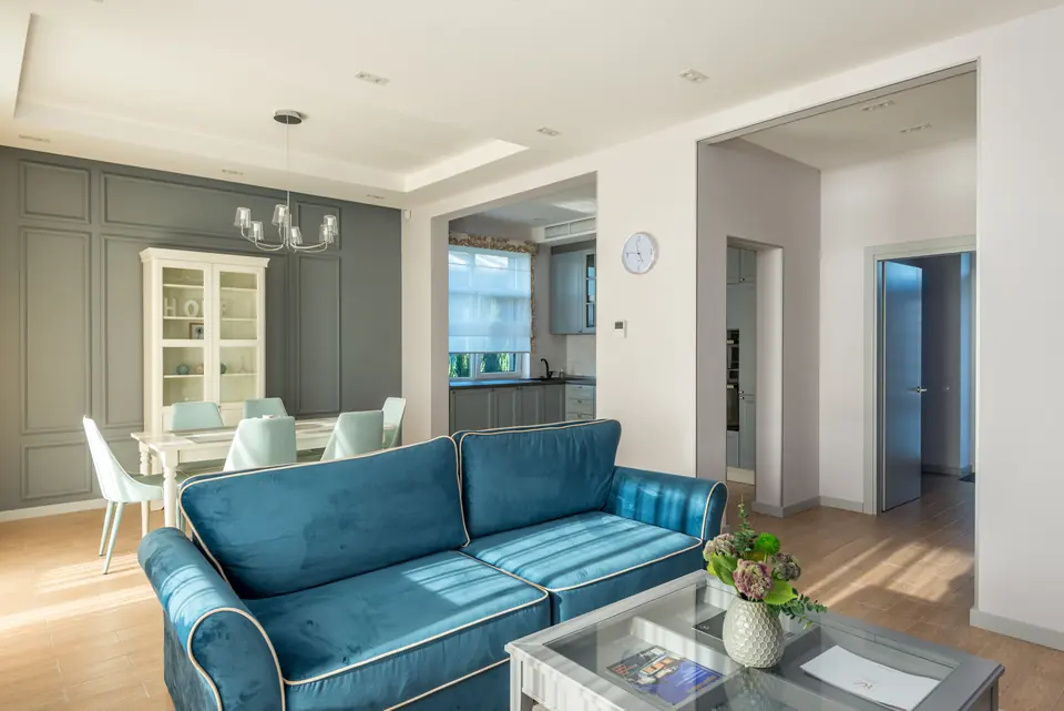 Fertig eingerichtetes, helles Wohnzimmer mit blauem Sofa
